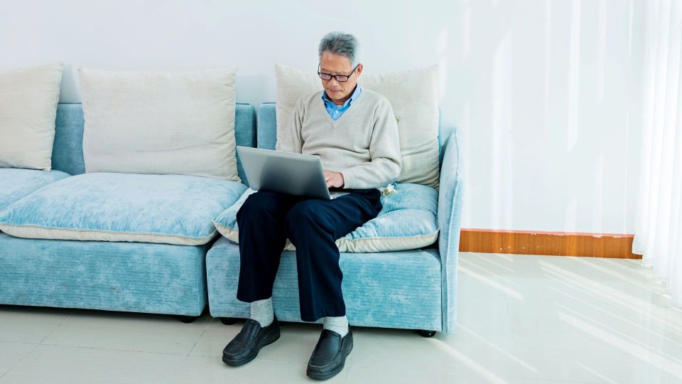 Senior asian man working on laptop at home.
