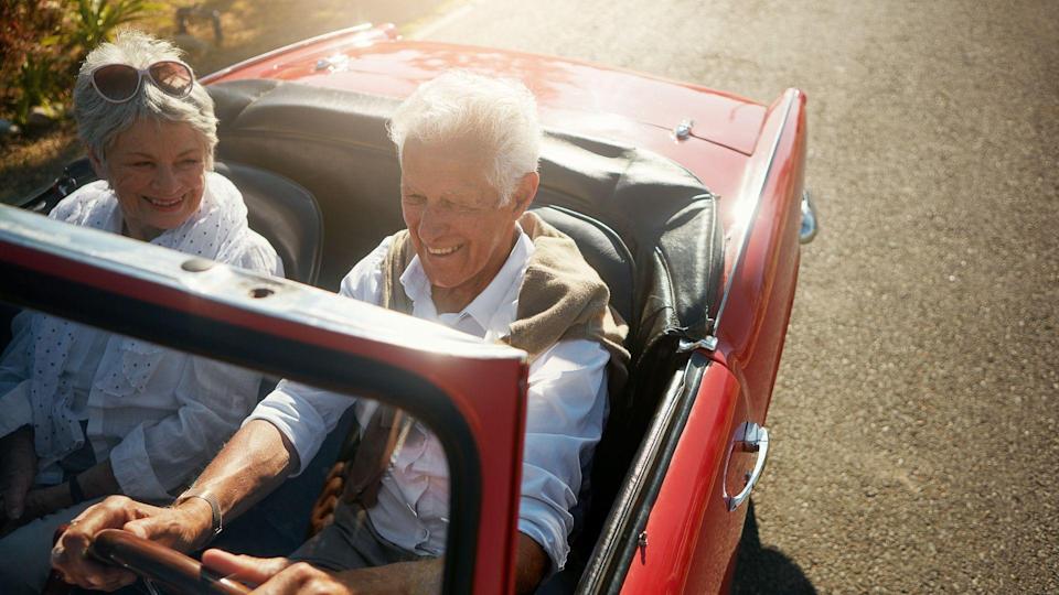 senior couple driving luxury new car in retirement