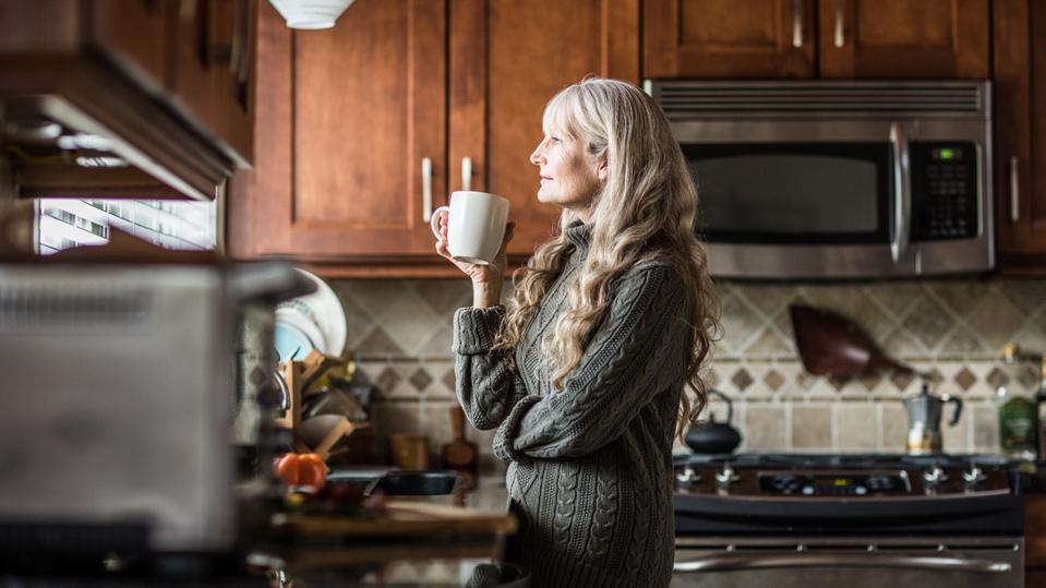 Portrait of woman (60yrs) having coffee in kitchen