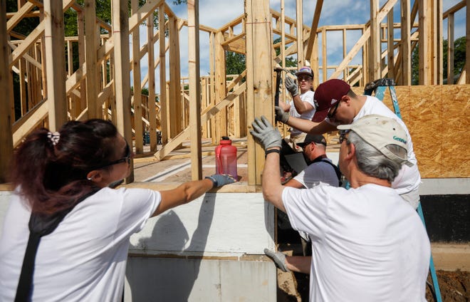 Volunteers work on a Habitat for Humanity house earlier this summer. The organization provides financial literacy training as part of its program to house people.