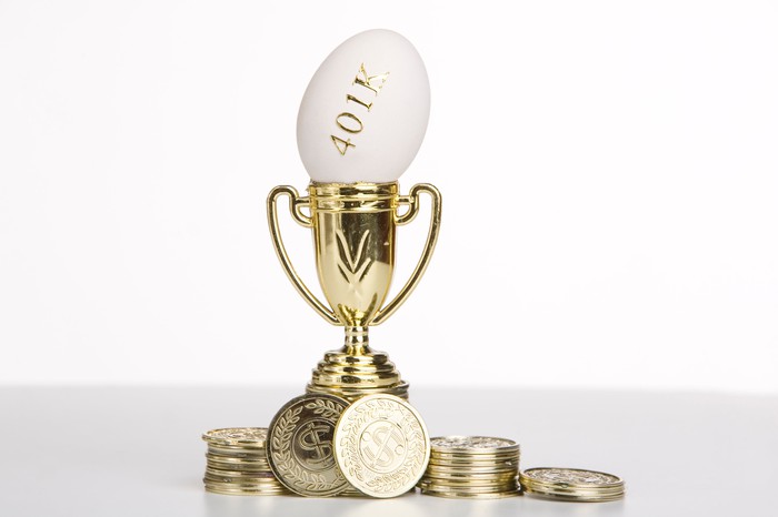 Egg with 401k written on it inside a trophy surrounded by golden coins