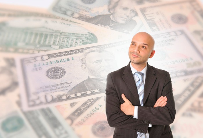A person is looking wistful, against a background of cash.